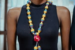 Close-up of a vibrant beaded necklace worn over a simple black dress, showcasing fashion elegance.